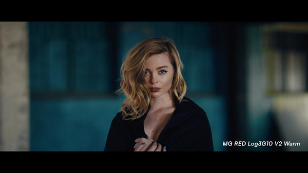 A blonde woman in a black top looks directly at the camera against a dark blue-toned blurred background. White text in the bottom right reads 'MG RED Log3G10 V2 Warm'.